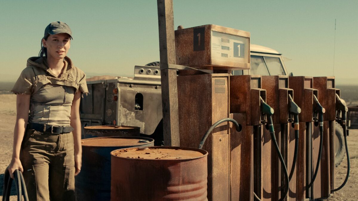 Dystrybutory z paliwem na pustkowiu i korzystająca z nich młoda dziewczyna.