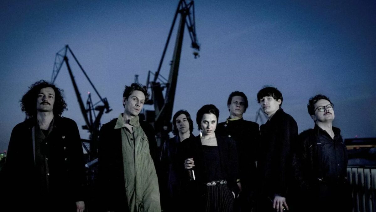 Grupa młodych ludzi na tle stoczni.