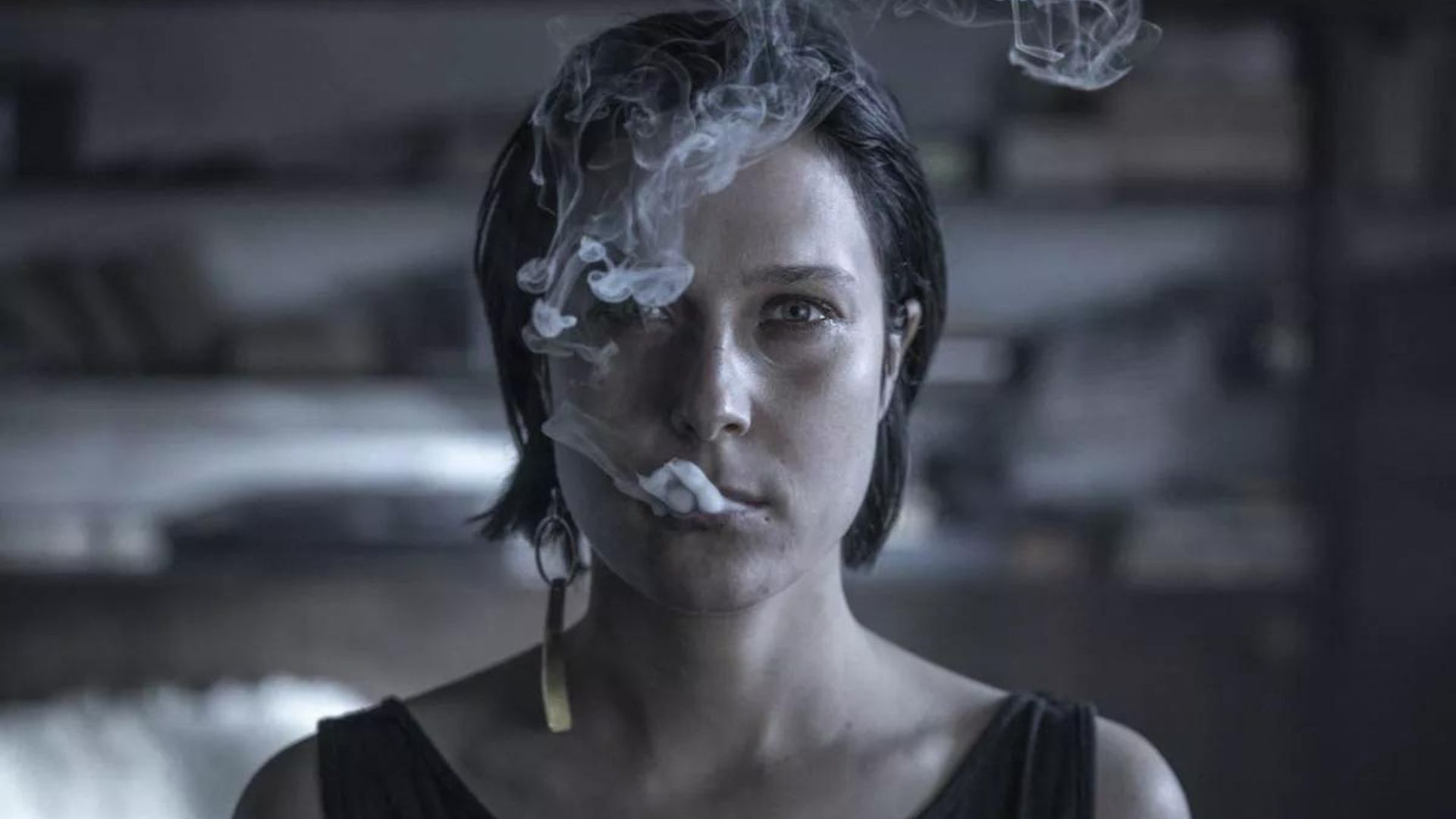 Zbliżenie na młodą kobietę palącą papierosa.