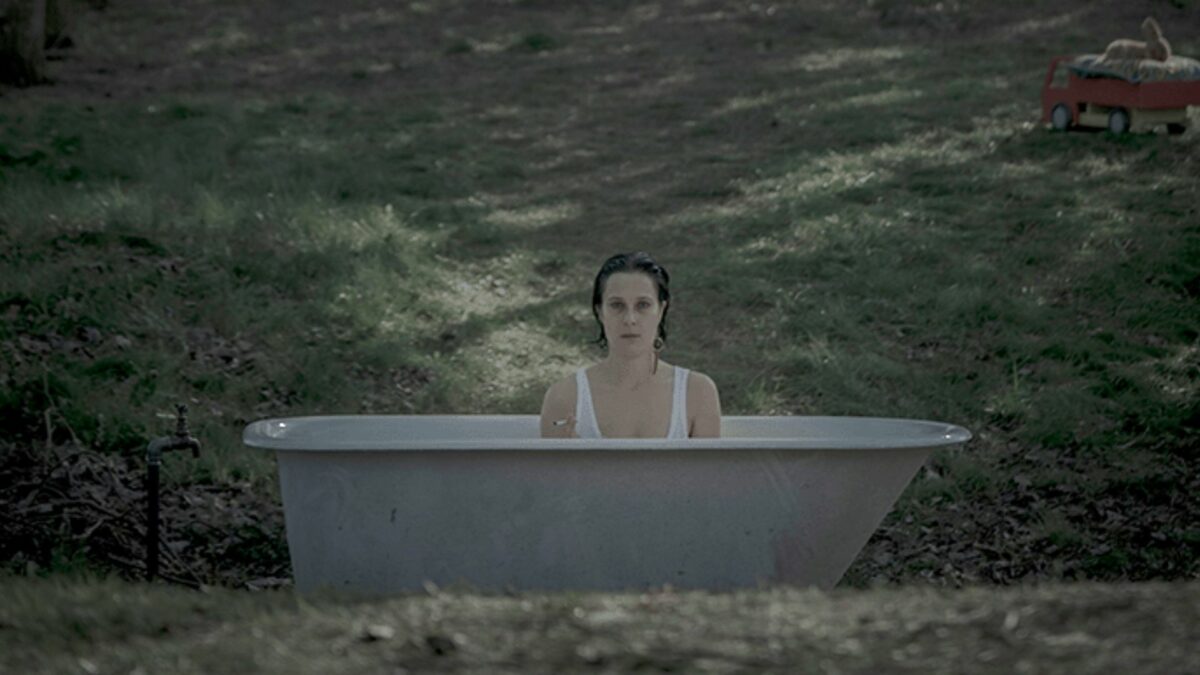 Kadr z młodą dziewczyną w wannie w samym srodku lasu.