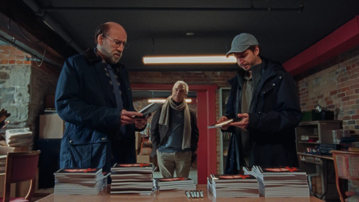 Trójka mężczyzn przy stole z książkami.