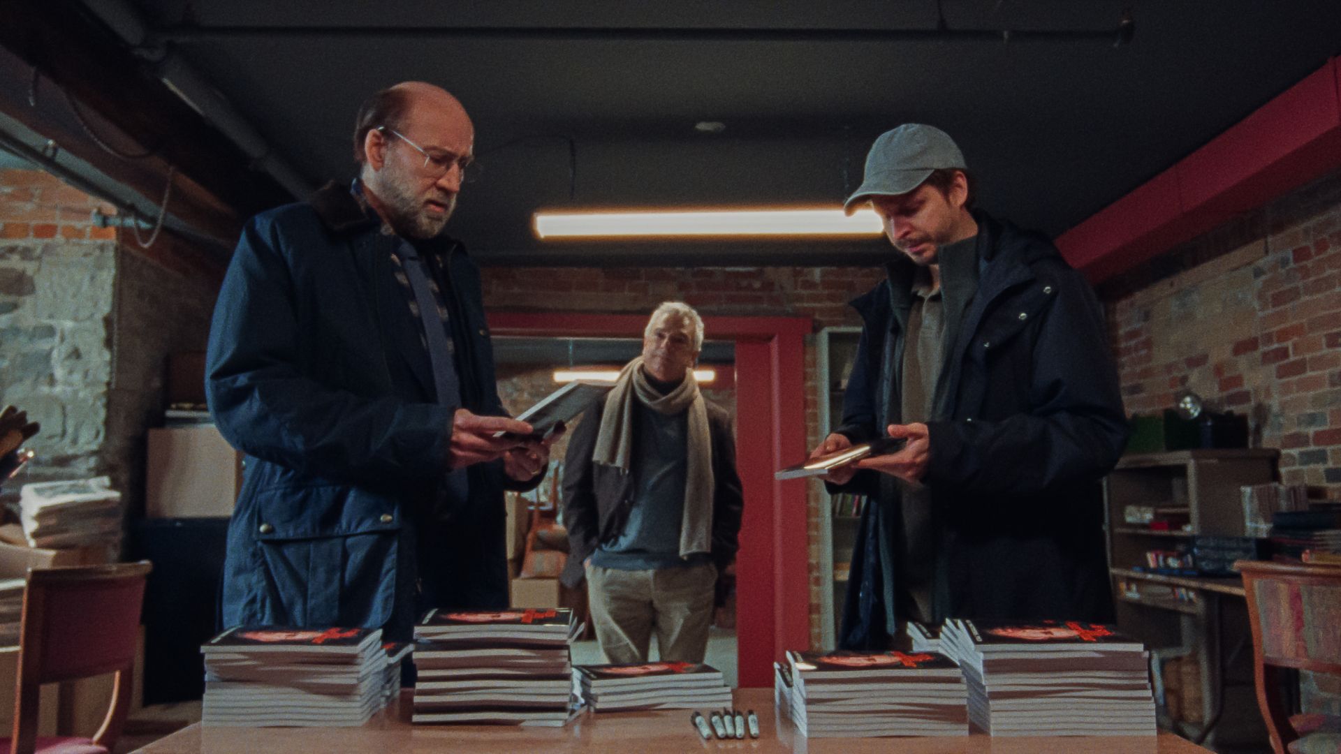 Trójka mężczyzn przy stole z książkami.