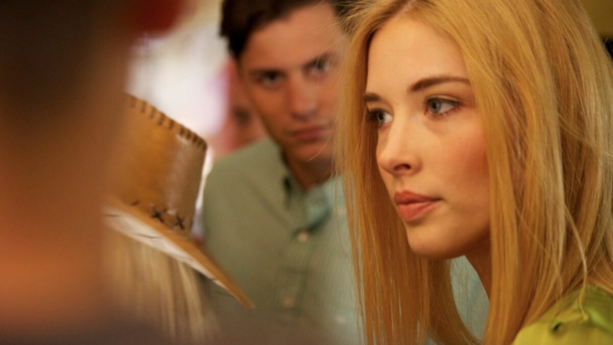 Zbliżenie na twarz młodej dziewczyny, w tle inne osoby.