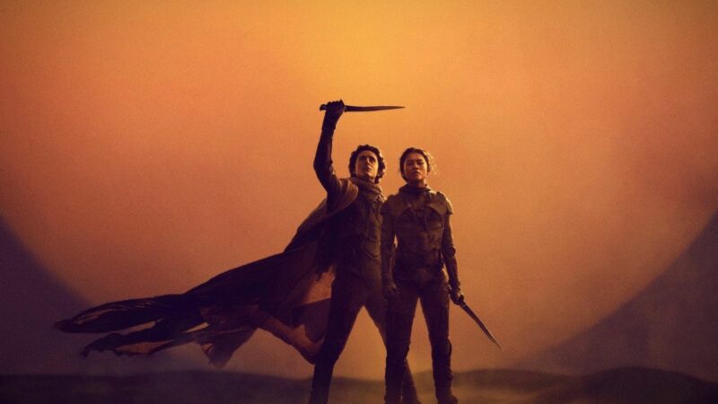 Chłopak w towarzystwie dziewczyny na pustyni na tle wschodzącej planety.