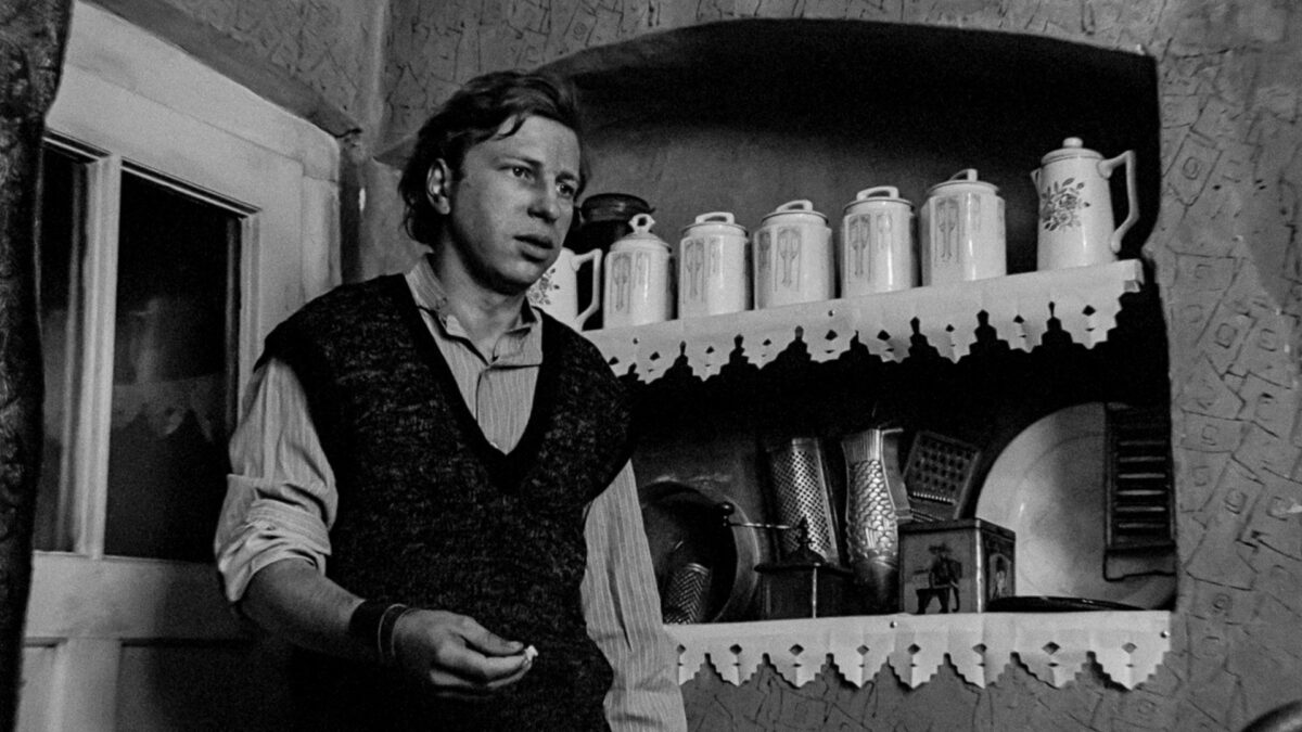 Młody chłopak stojący przed kuchennym kredensem.