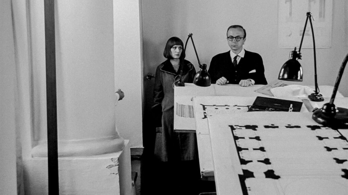 Para siedząca przed biurkiem z planami architektonicznymi.