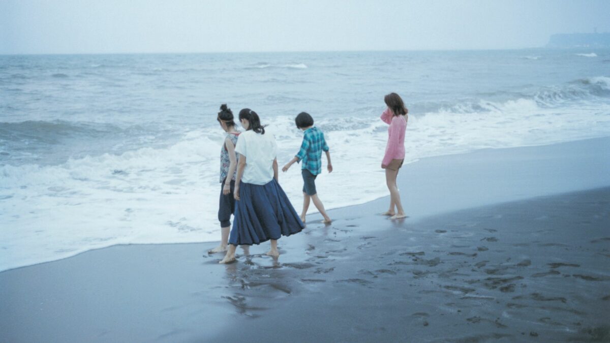 Kadr przedstawiający cztery siostry spacerujące po plaży.