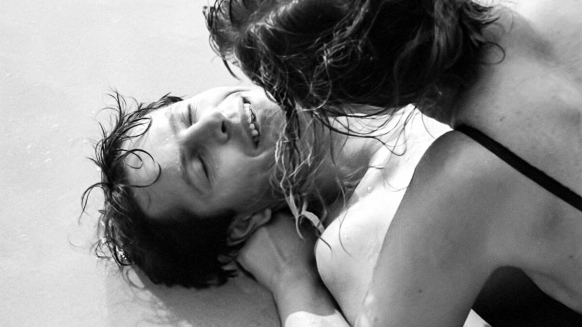 Kadr z parą spędzającą radosne chwilę nad morzem.