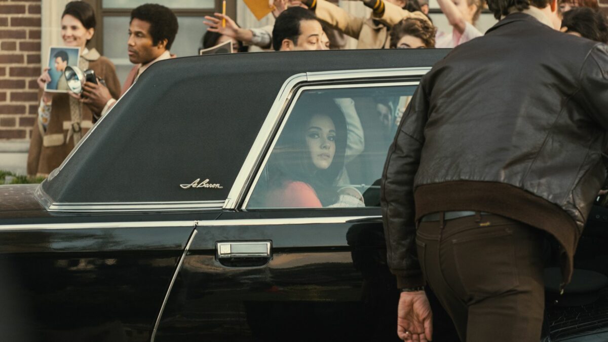 Samochód z młodą gwiazdą otoczony dziennikarzami.