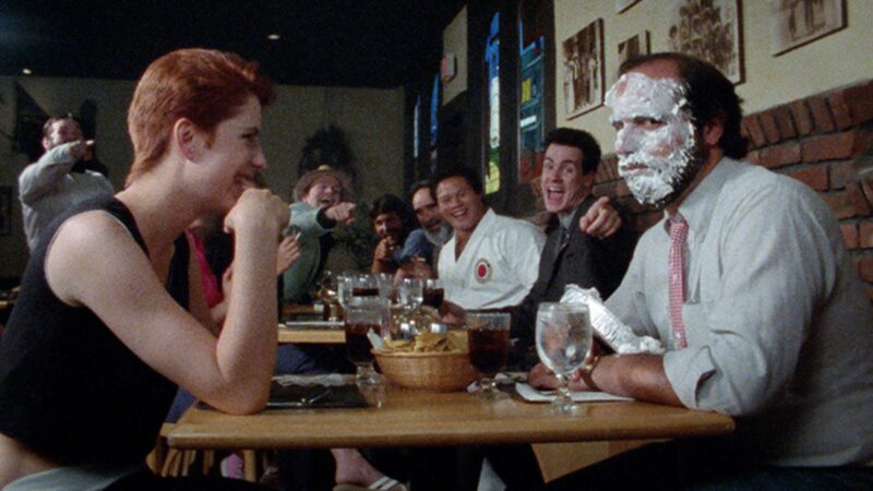 Kadr z baru, przy stole siedzi dwóch mężczyzn, jeden ma na całej twarzy krem z tortu.