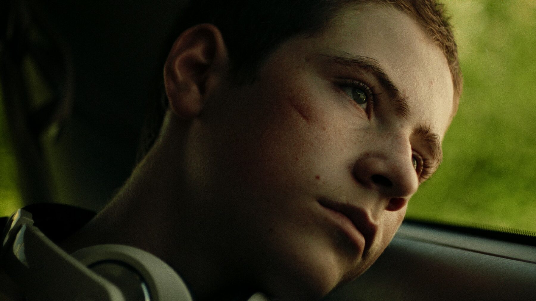 Zbliżenie na twarz młodego chłopaka siedzącego w samochodzie.
