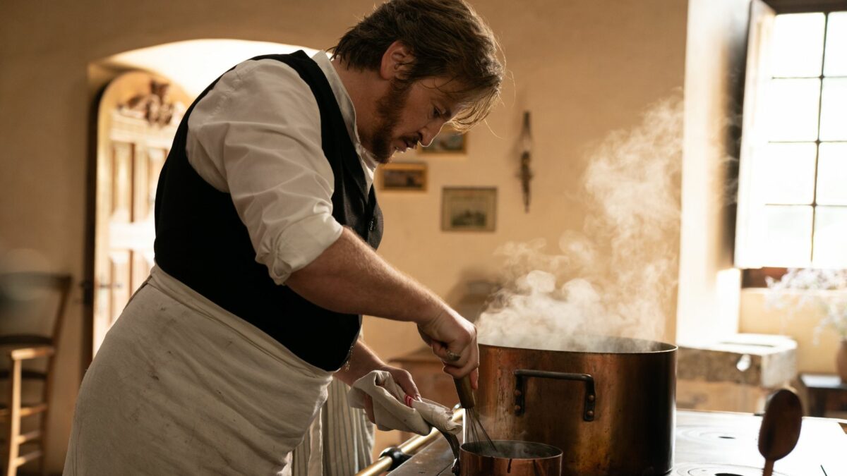 Mężczyzna w białym fartuchu gotujący zupę.