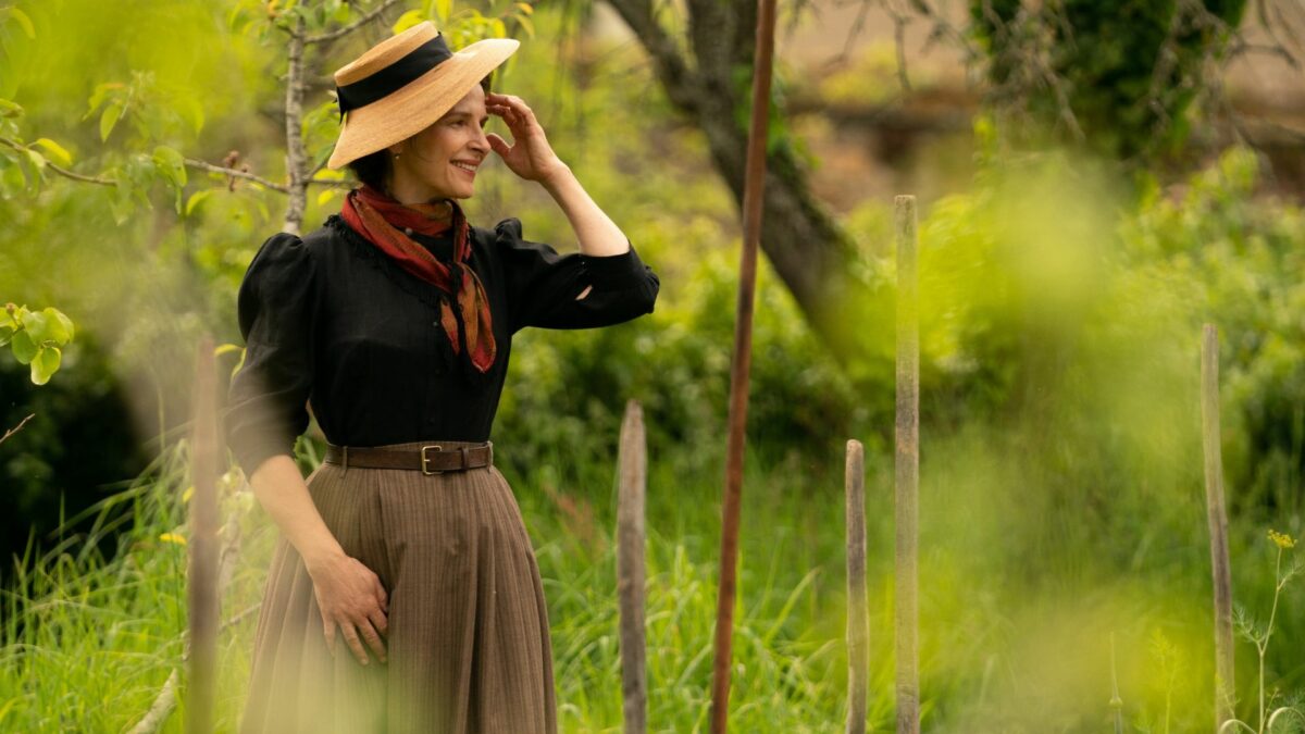 Kobieta w kapeluszu na spacerze w parku.