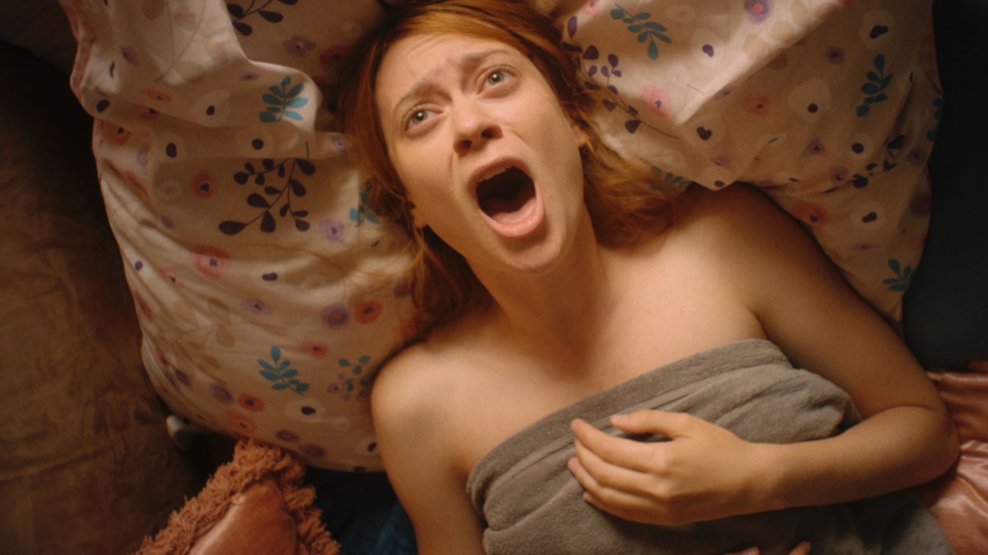 Kobieta w łóżku, na jej twarzy maluje się krzyk.