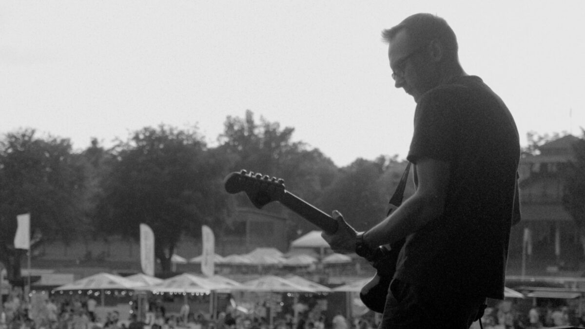 Czarno-biały kadr z mężczyzną grającym na gitarze