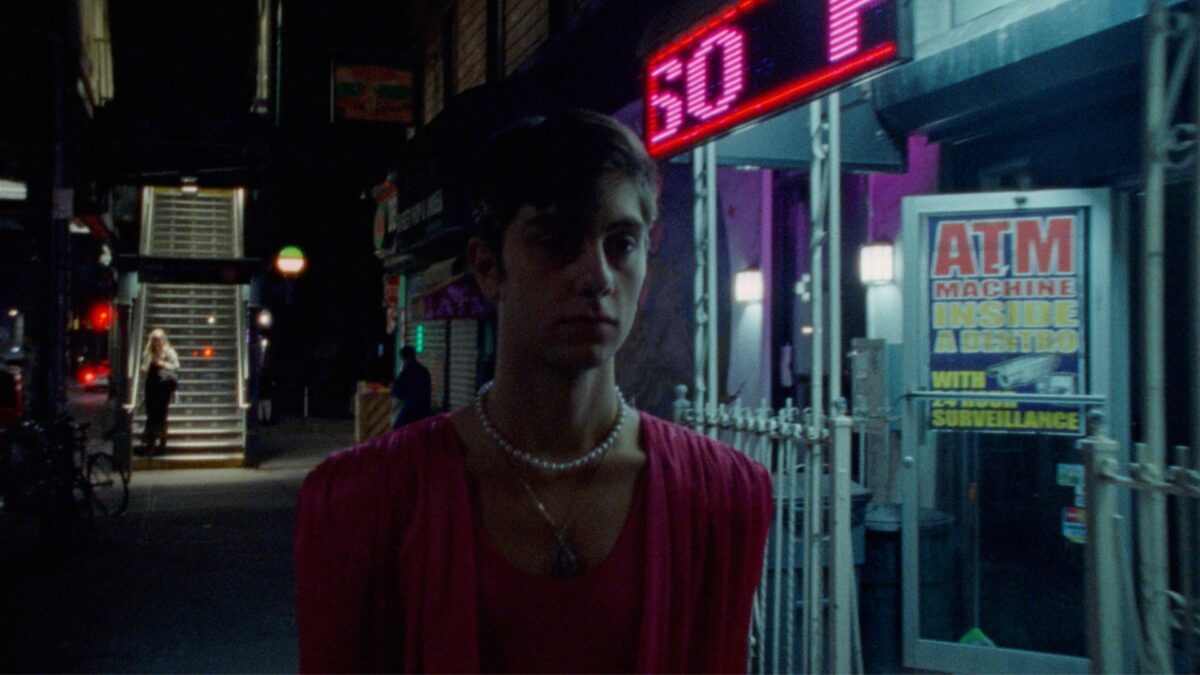 Chłopak mija kiosk z bankomatem i neon