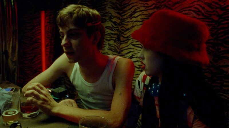 Chłopak siedzi z dziewczyną w czerwonym kapeluszu w barze