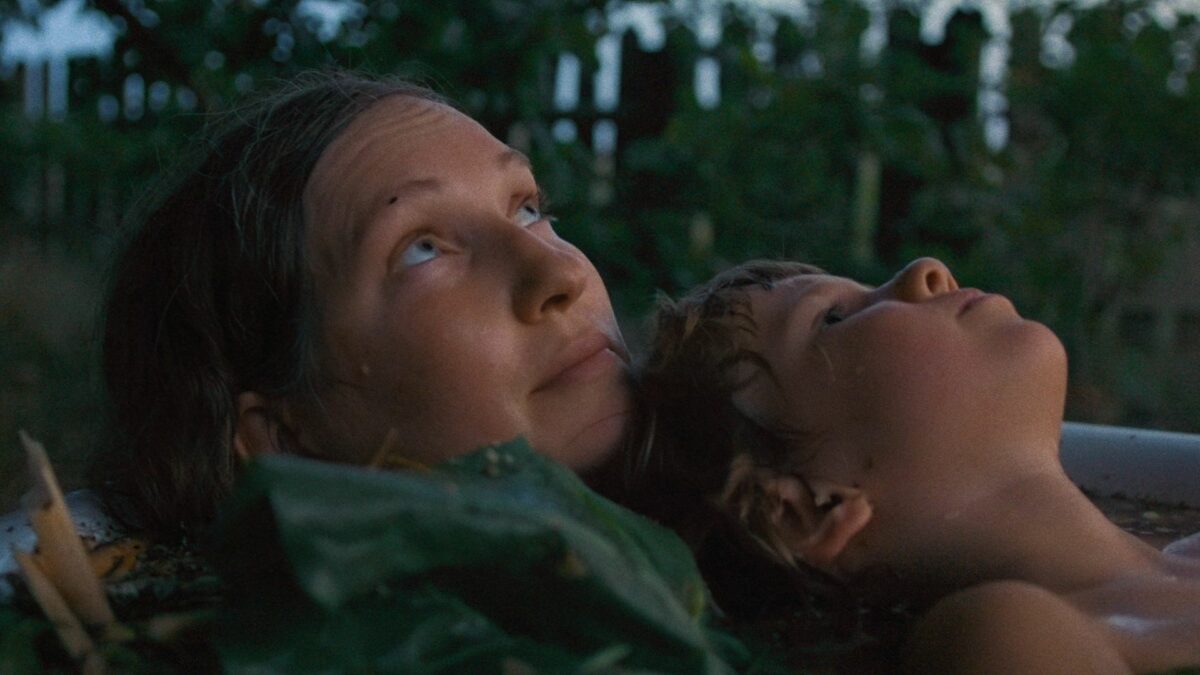 Kobieta oraz dziecko leżą razem w zbiorniku z wodą i patrzą w górę