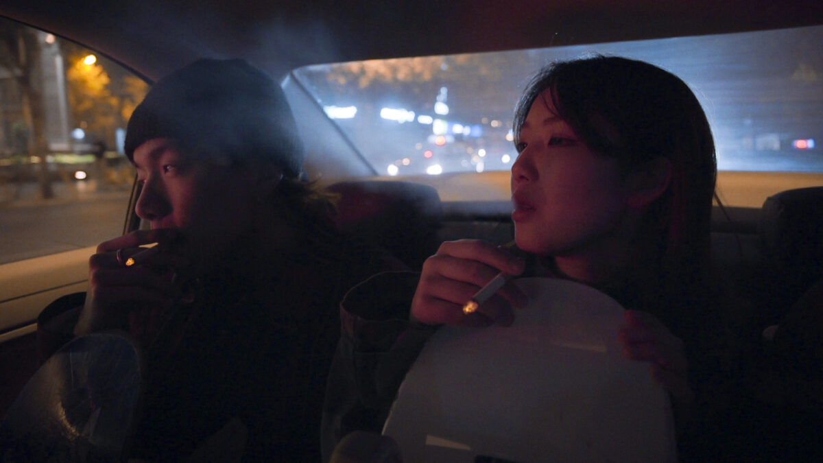 Para siedzi w samochodzie na miejscu pasażerskim i pali papierosy