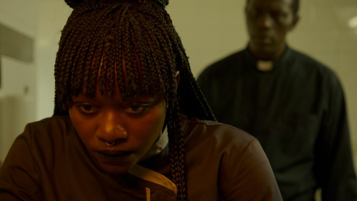 Wychodząca kobieta a za nią widać postać księdza.