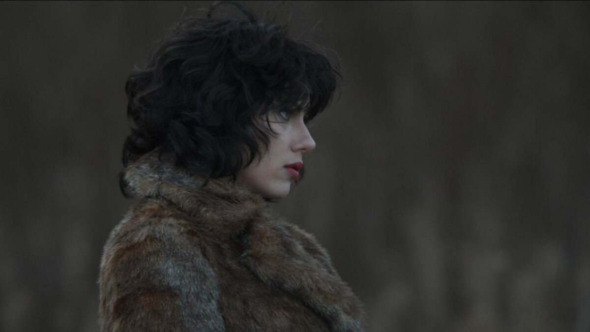 Kobieta w futrze przechodząca przez las.