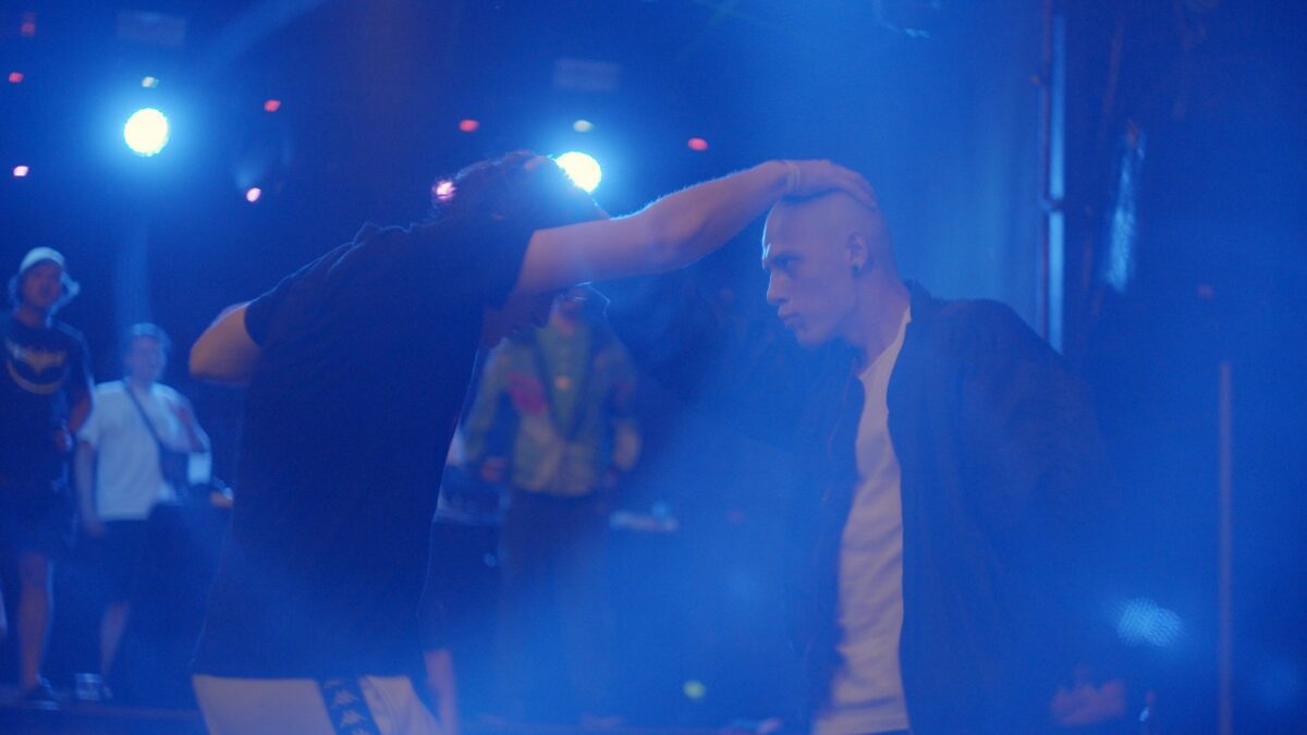 Tańczący mężczyźni w niebieskim świetle chwytają się nawzajem za głowy