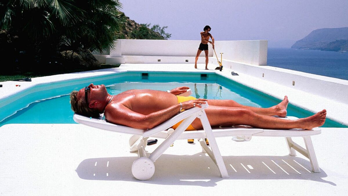 Mężczyzna wypoczywający na leżaku przy basenie.