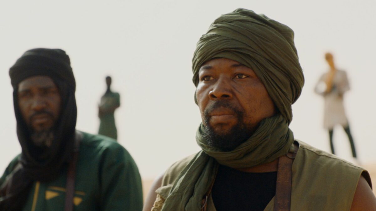 Grupa uzbrojonych mężczyzn na pustyni.