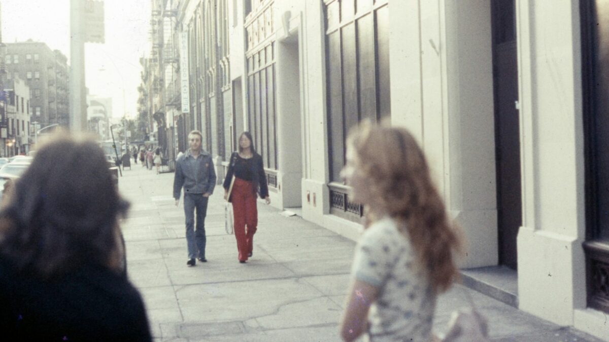 Kadr przedstawiający kobietę i mężczyznę spacerujących po chodniku