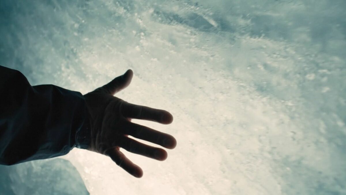 Ludzka dłoń dotyka oblodzonej powierzchni