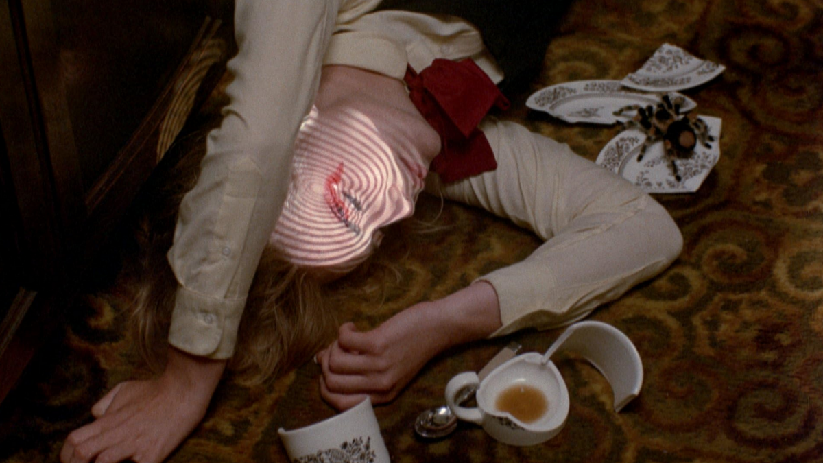 Kobieta na podłodze a obok rozbita filiżanka i duży pająk.