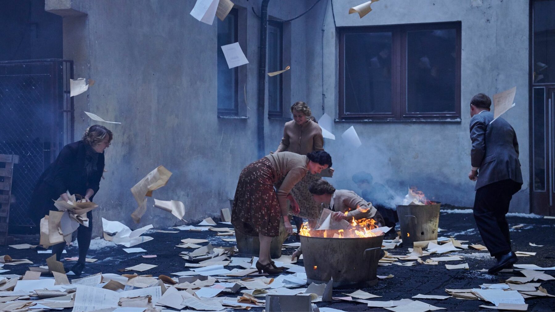 Mieszkańcy kamienicy palą dokumenty na podwórku.