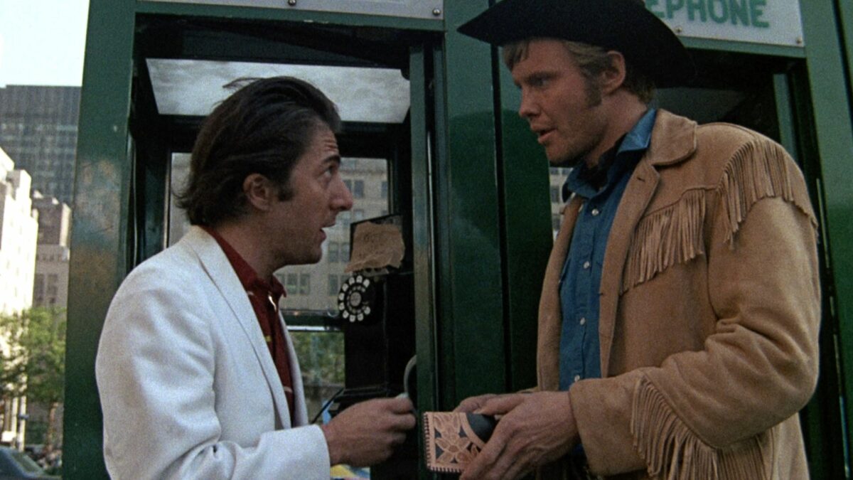 Rozmawiający mężczyźni przed budką telefoniczną.