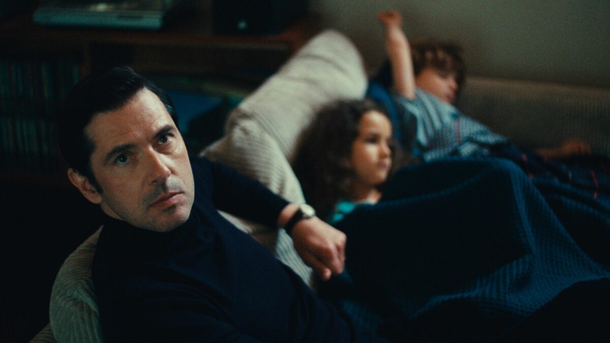 Mężczyzna na kanapie a obok niego dwójka dzieci/