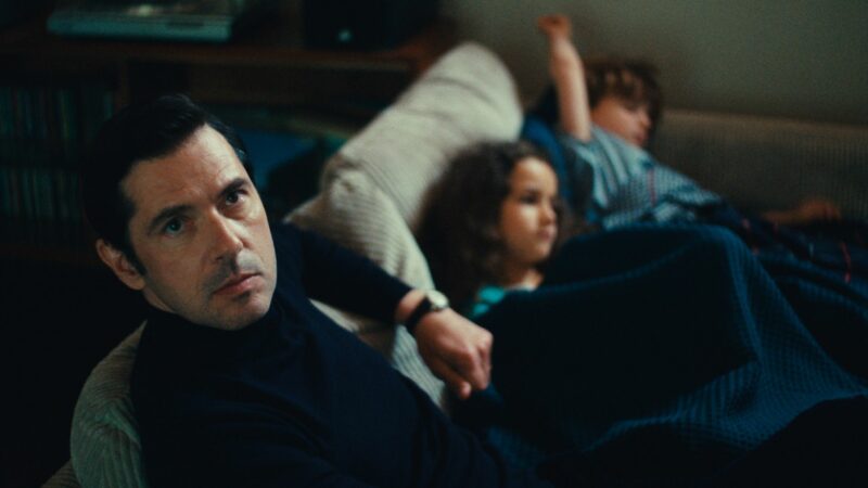 Mężczyzna na kanapie a obok niego dwójka dzieci/