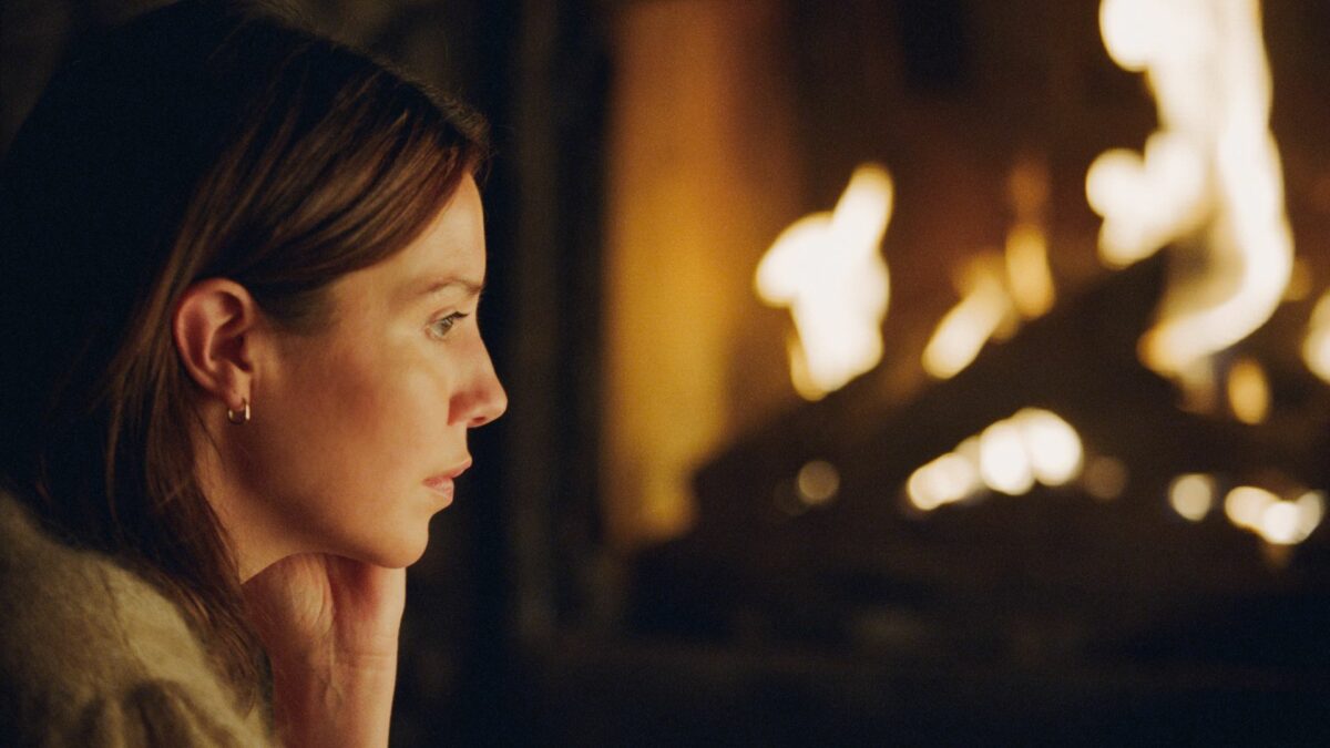 Zbliżenie na twarz kobiety przy kominku.