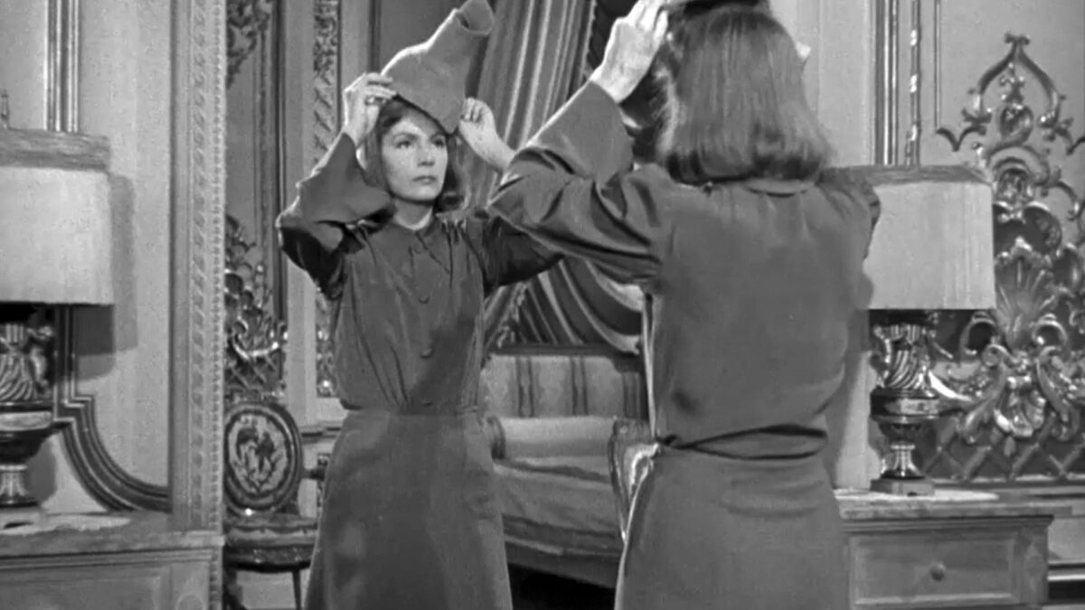 Kobieta przed lustrem przymierzająca kapelusz.