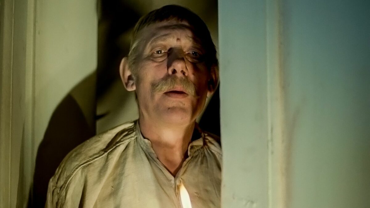 Mężczyzna zakradający się nocą, w dłoni trzyma świecę.