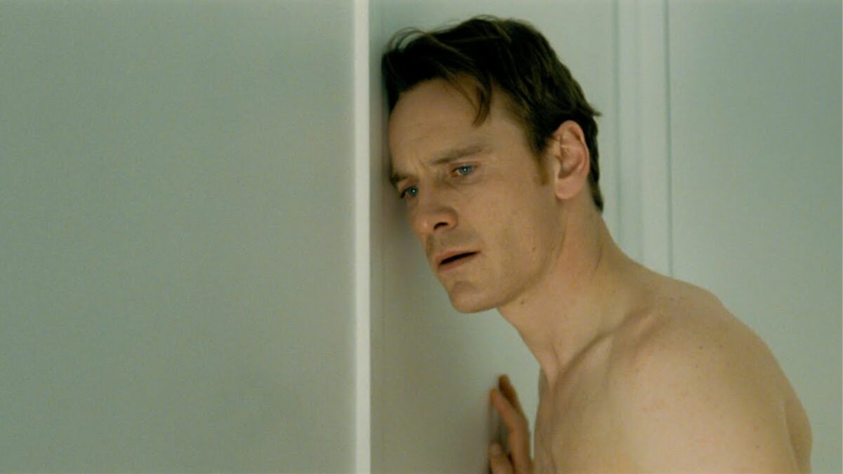 Podsłuchujący mężczyzna pod ścianą.