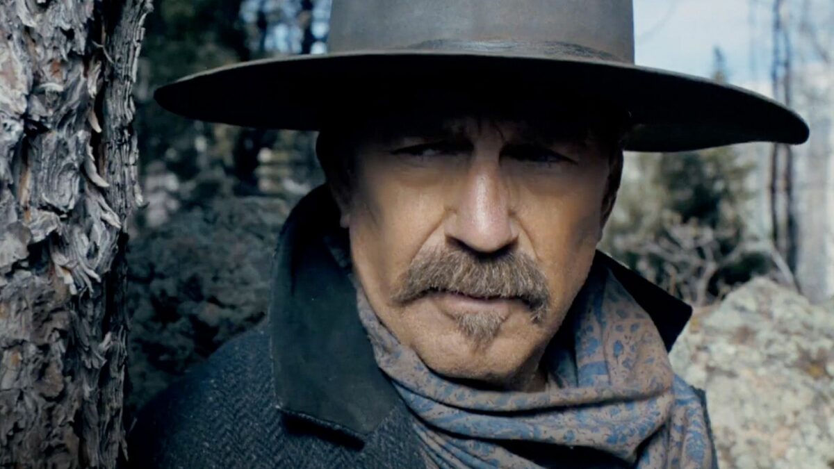 Portret mężczyzny w kapeluszu na tle lasu.