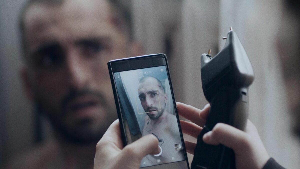 Dziewczyna robi zdjęcie chłopakowi, trzyma telefon a w drugiej dłoni paralizator.