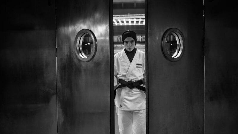 Zawodniczka judo w burkini wychodzi na hale sportową.