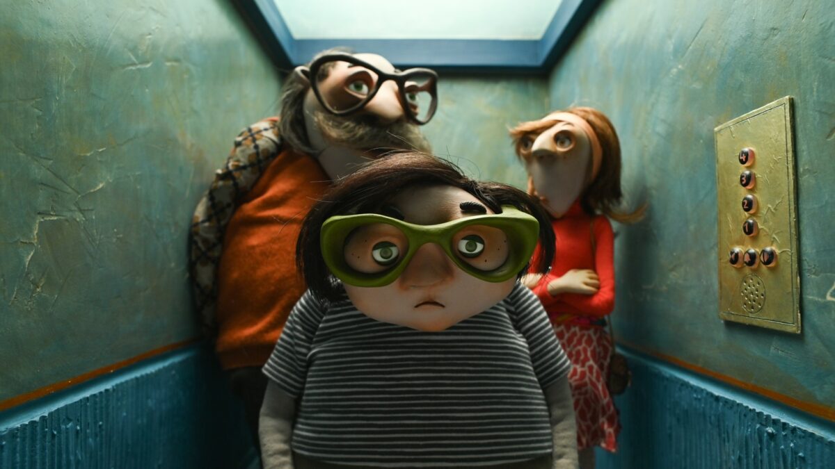 Kadr z bajki, scena z windy a w niej młody chłopak a za nim dwójka dorosłych.