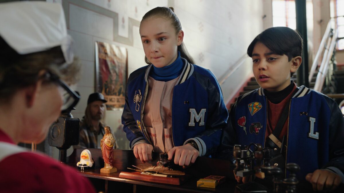 Dziewczynka w towarzystwie chłopca załatwiają sprawę przy ladzie.