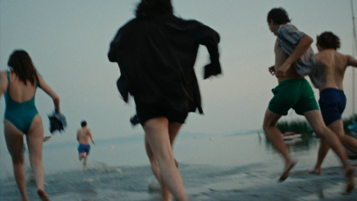 Grupa młodych ludzi biegnąca do morza.