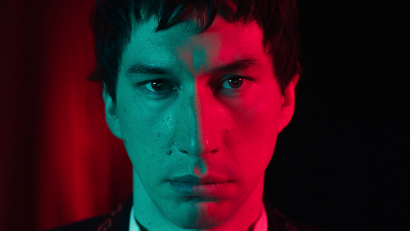 Zbliżenie na twarz mężczyzny oświetloną neonami.