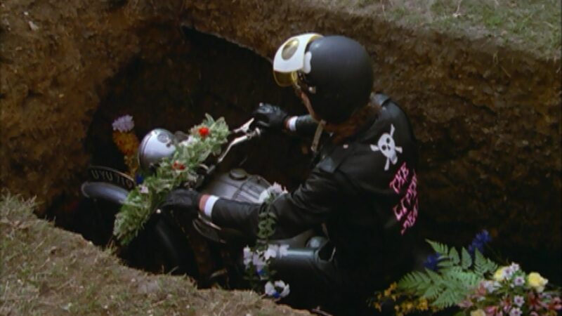 Motocyklista siedzący na motorze w grobie ziemnym.