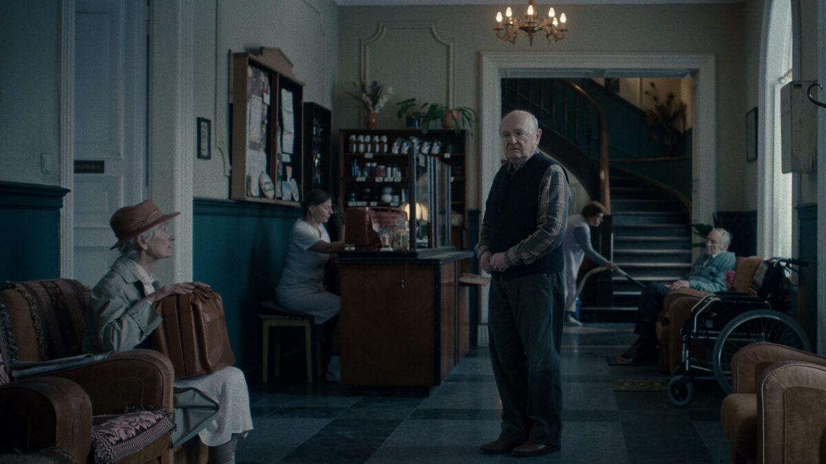 Zagubiony starszy mężczyzna w korytarzu domu opieki.