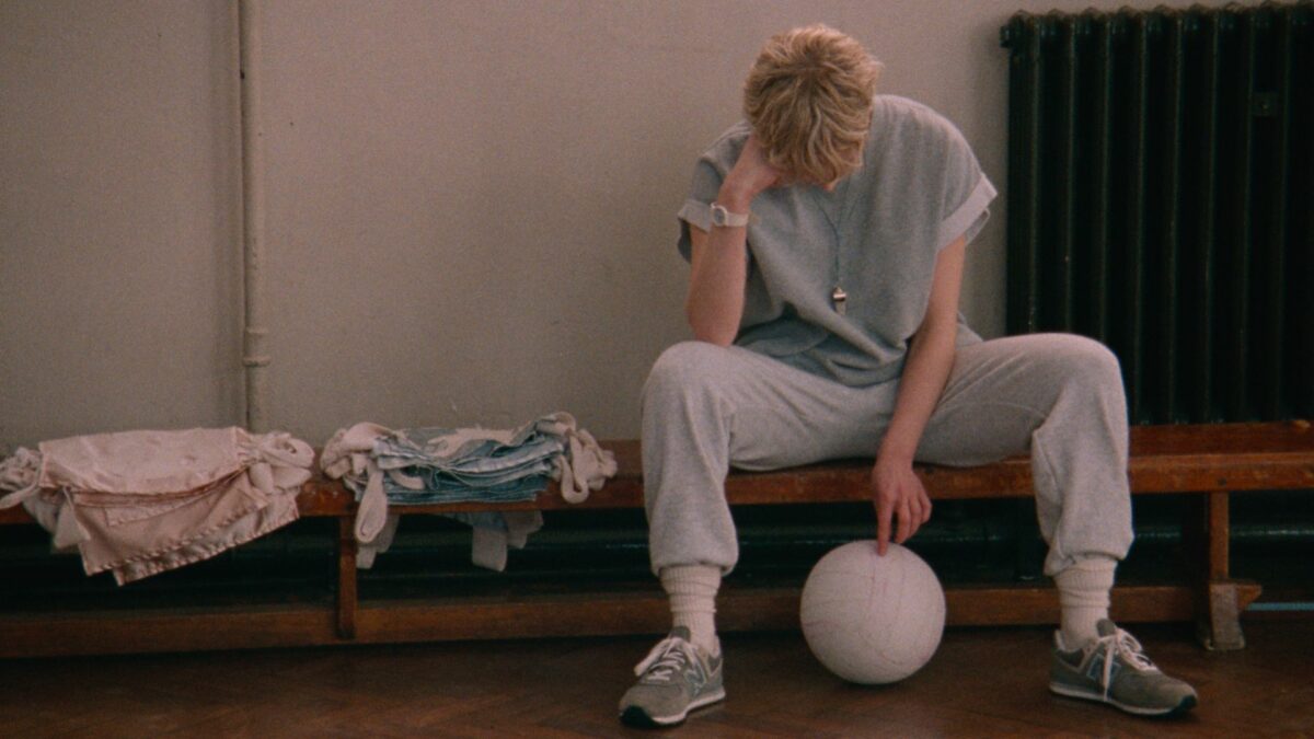 Kobieta siedząca na ławce, dotykająca piłkę.