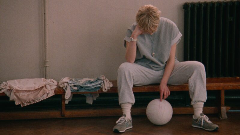 Kobieta siedząca na ławce, dotykająca piłkę.